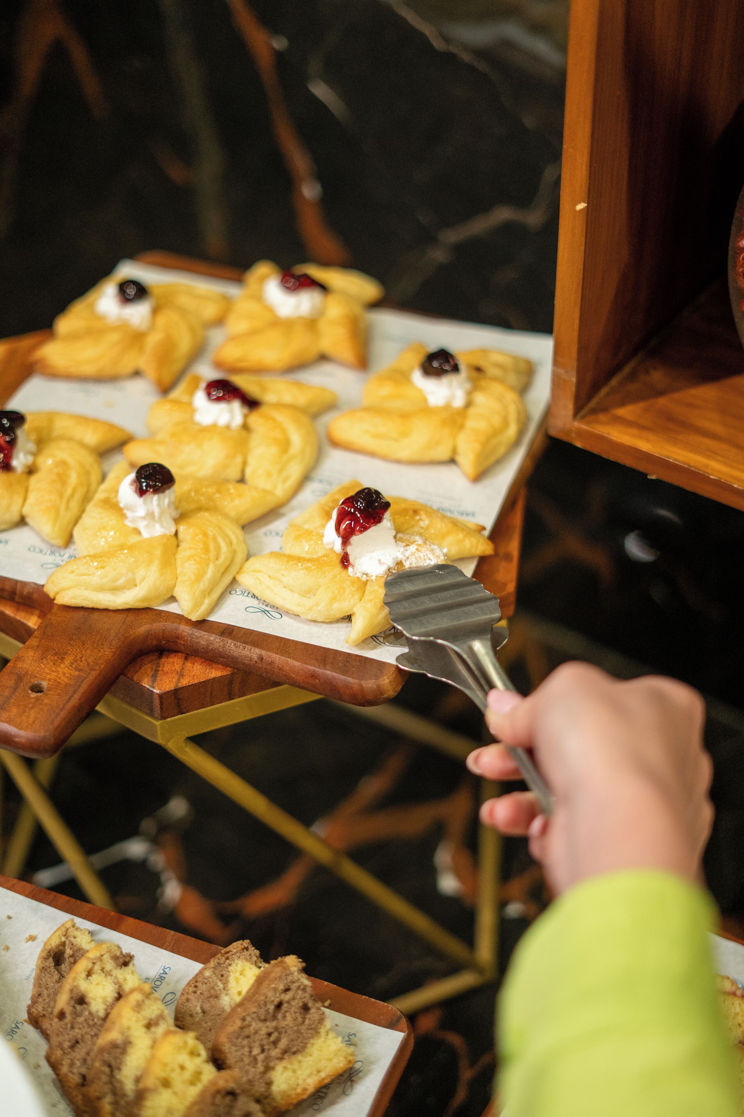 A person serving pastries on a wooden board.