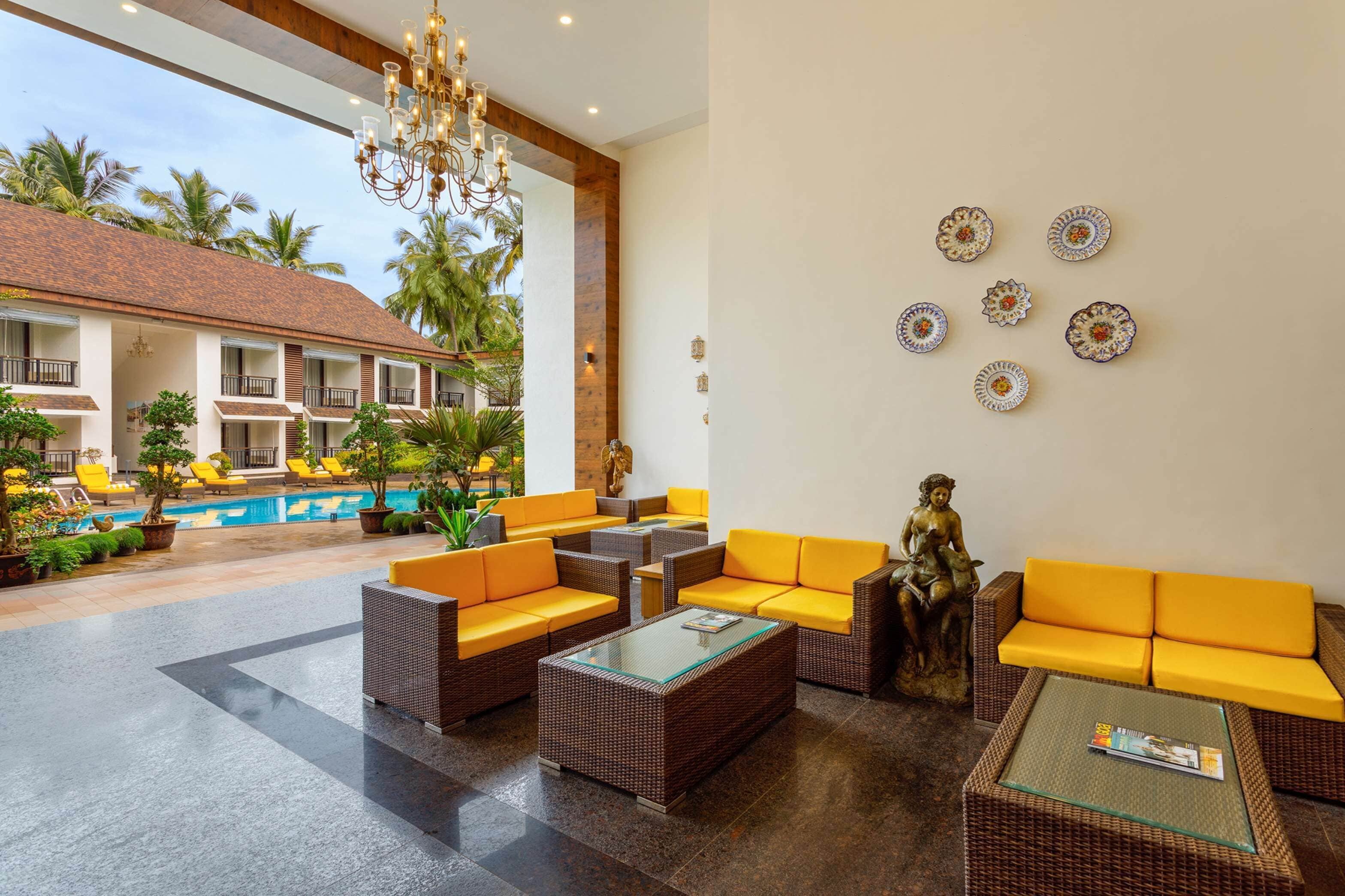 A lobby with wicker furniture, a pool, and a statue.
