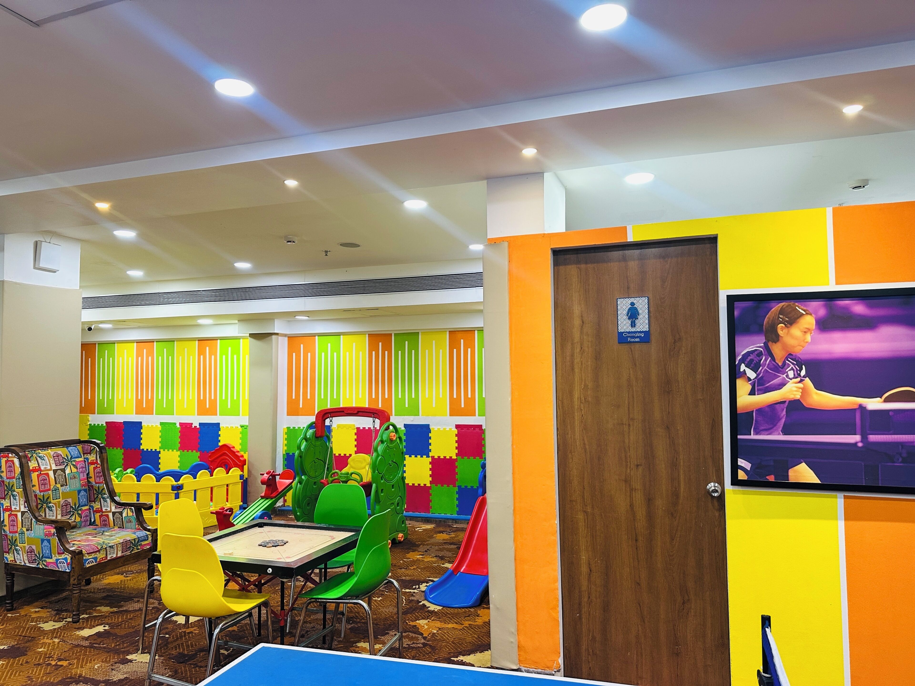 Un área de juegos infantiles con paredes de colores, una mesa de ping pong y una pantalla de televisión.