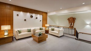 A spacious living room with two cream-colored sofas, a wooden coffee table, and a large elephant sculpture on the wall. - Sobit Sarovar Portico Goa (Canacona)