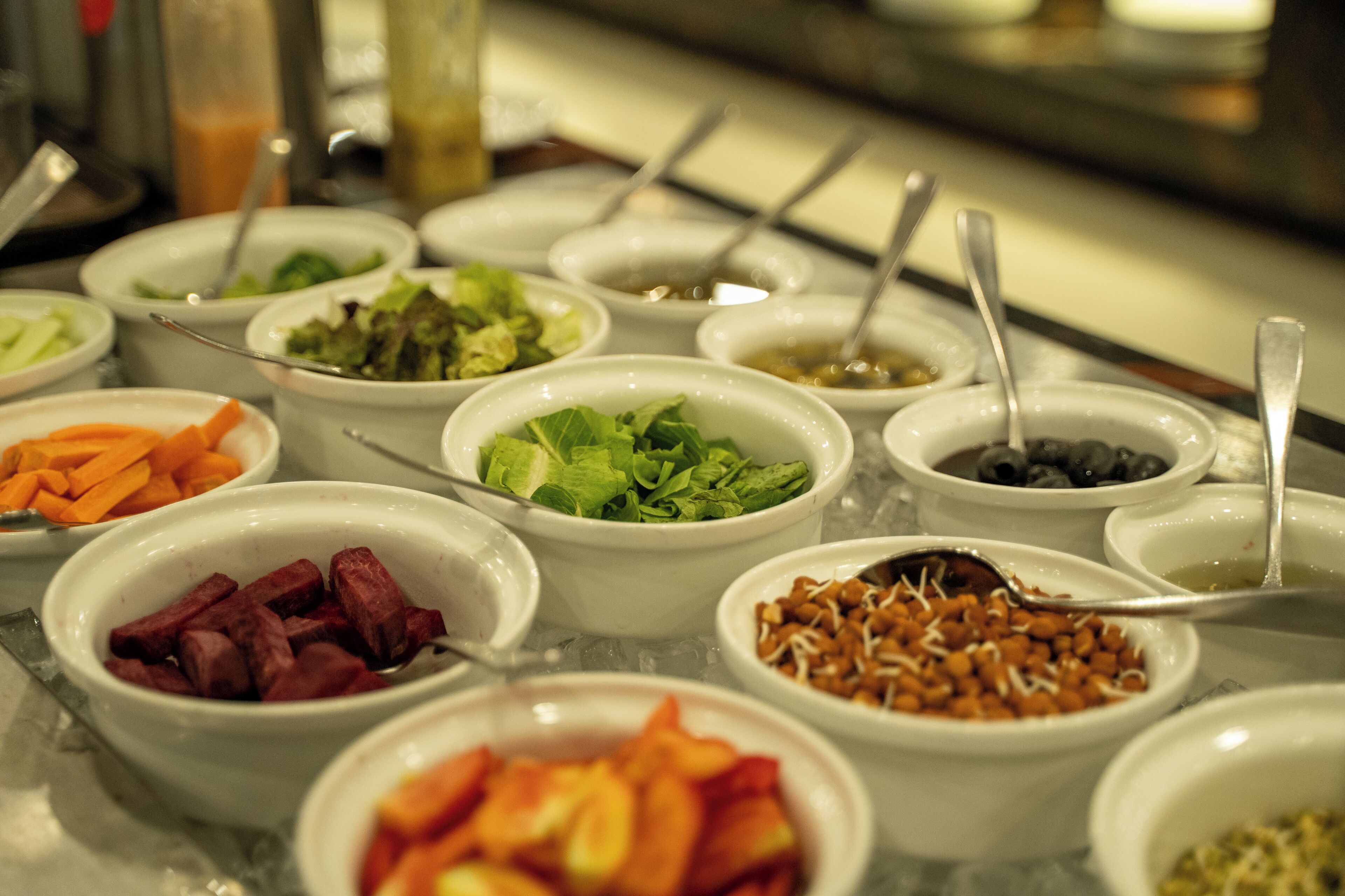A buffet with various food items in bowls, including salads, fruits, and other dishes.