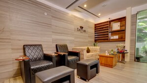 A modern spa room with leather seating, a reception desk, and a wooden wall with a spa logo. - Sobit Sarovar Portico Goa (Canacona)