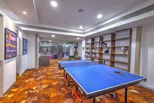 Una habitación con mesas de ping pong, estanterías y una alfombra estampada.