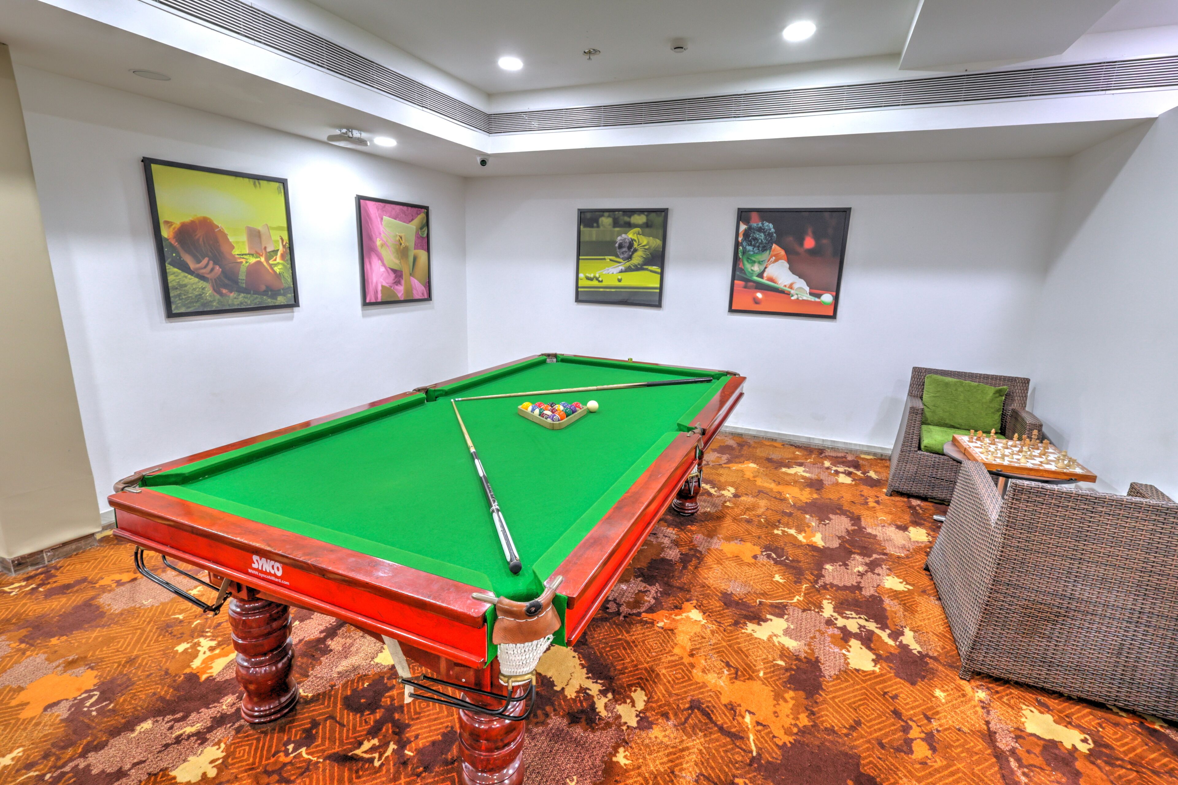 A pool table with a green felt surface, surrounded by a patterned carpet.