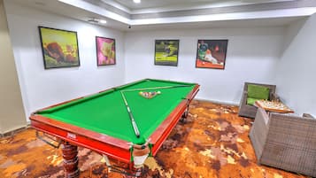 A pool table with a green felt surface, surrounded by a patterned carpet.