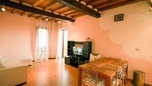 Ein Wohnzimmer mit Holzboden, einem Fernseher, einem Esstisch mit Stühlen und einer Couch.