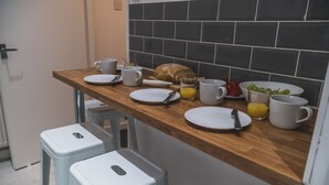 Una cocina con encimera de madera, taburetes blancos y salpicadero de azulejos.