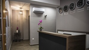 Un'area reception moderna con scrivania in legno, impianto di condizionamento e orologi che mostrano l'ora di diverse città.