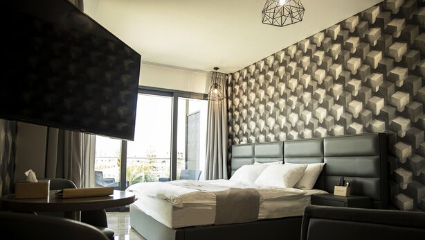 Una camera d'albergo moderna con un letto grande, una televisione, una scrivania e vista sulla città.