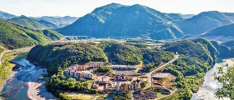 Un pueblo a orillas del río, con edificios a lo largo de la ribera, rodeado de colinas.