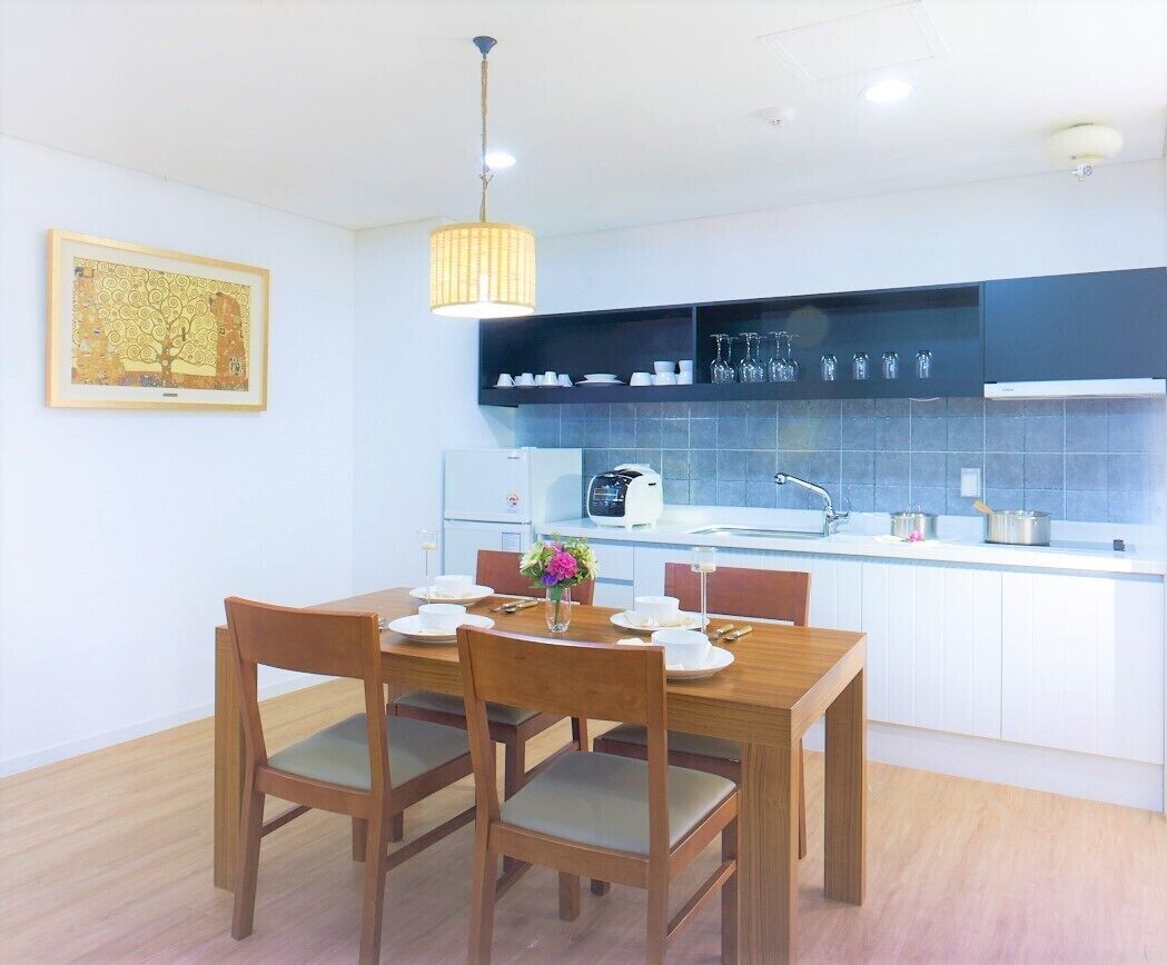 Cozinha moderna com mesa de jantar posta para dois, cafeteira e luminária pendente.