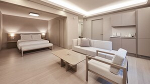Een moderne hotelkamer met een bed, een bank, een bijzettafeltje en een kitchenette.