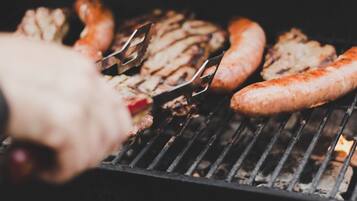 A close-up of a grill with sausages and meat being cooked.