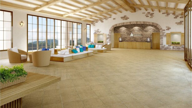 Een ruime lobby met een hoge plafond, grote ramen en een receptiegedeelte met een stenen open haard.