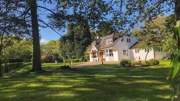 A two-story house with a white exterior, surrounded by a well-maintained lawn and trees.