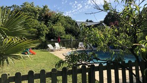 Un patio trasero con piscina, una valla de madera y una casa al fondo.