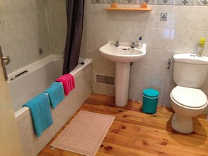 A bathroom with a bathtub, sink, toilet, and a small trash bin. - Chambres d'hotes Bastia et Bonifacio (Retiers)