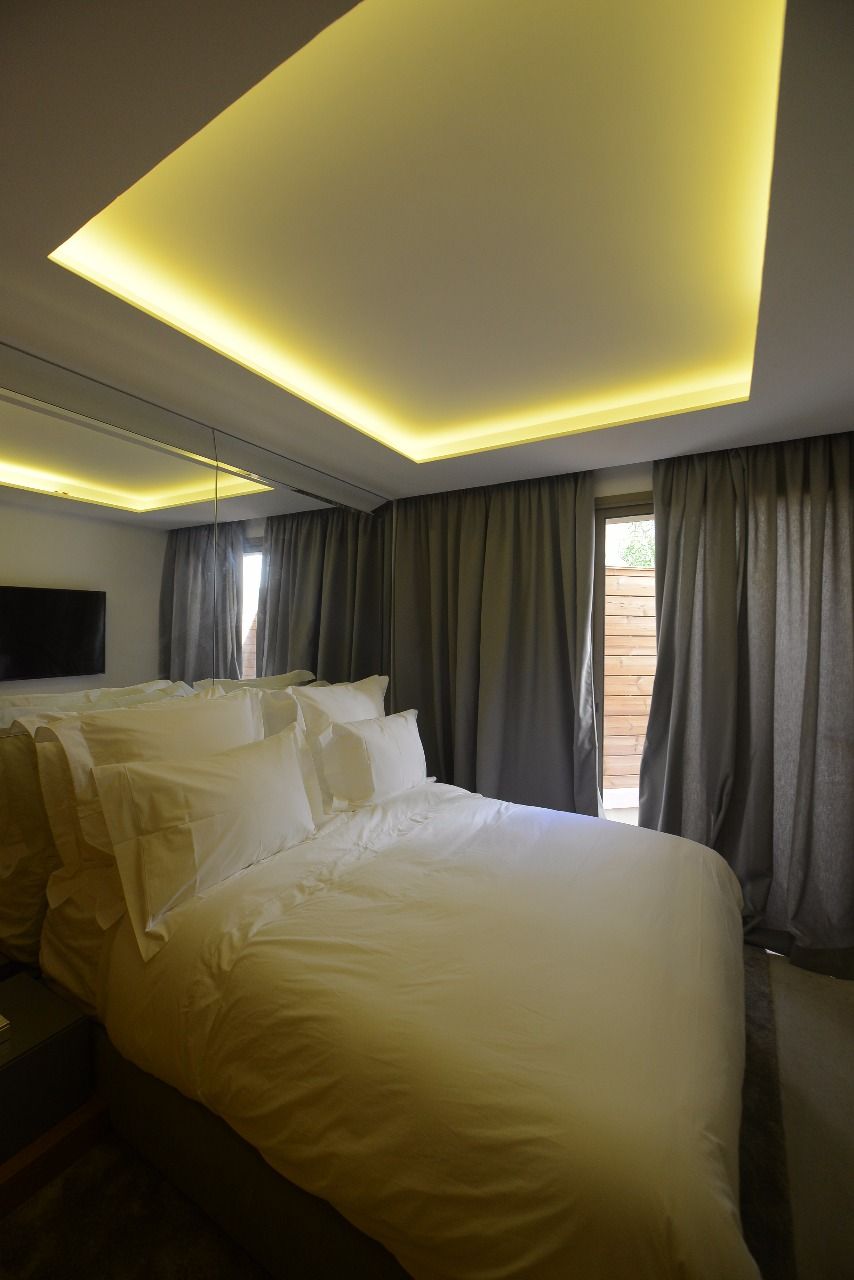 Une chambre d’hôtel avec un grand lit, un téléviseur à écran plat fixé au mur et une fenêtre avec des rideaux.