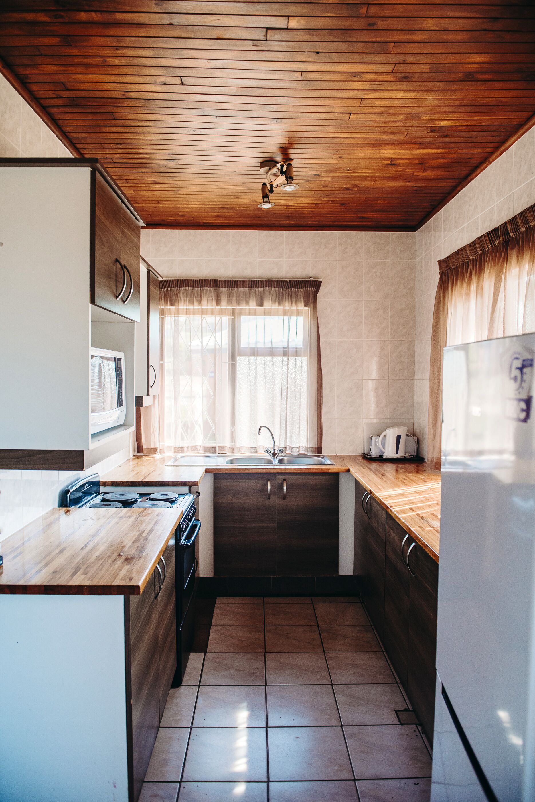 Una cocina compacta con muebles de madera, estufa empotrada y pileta.
