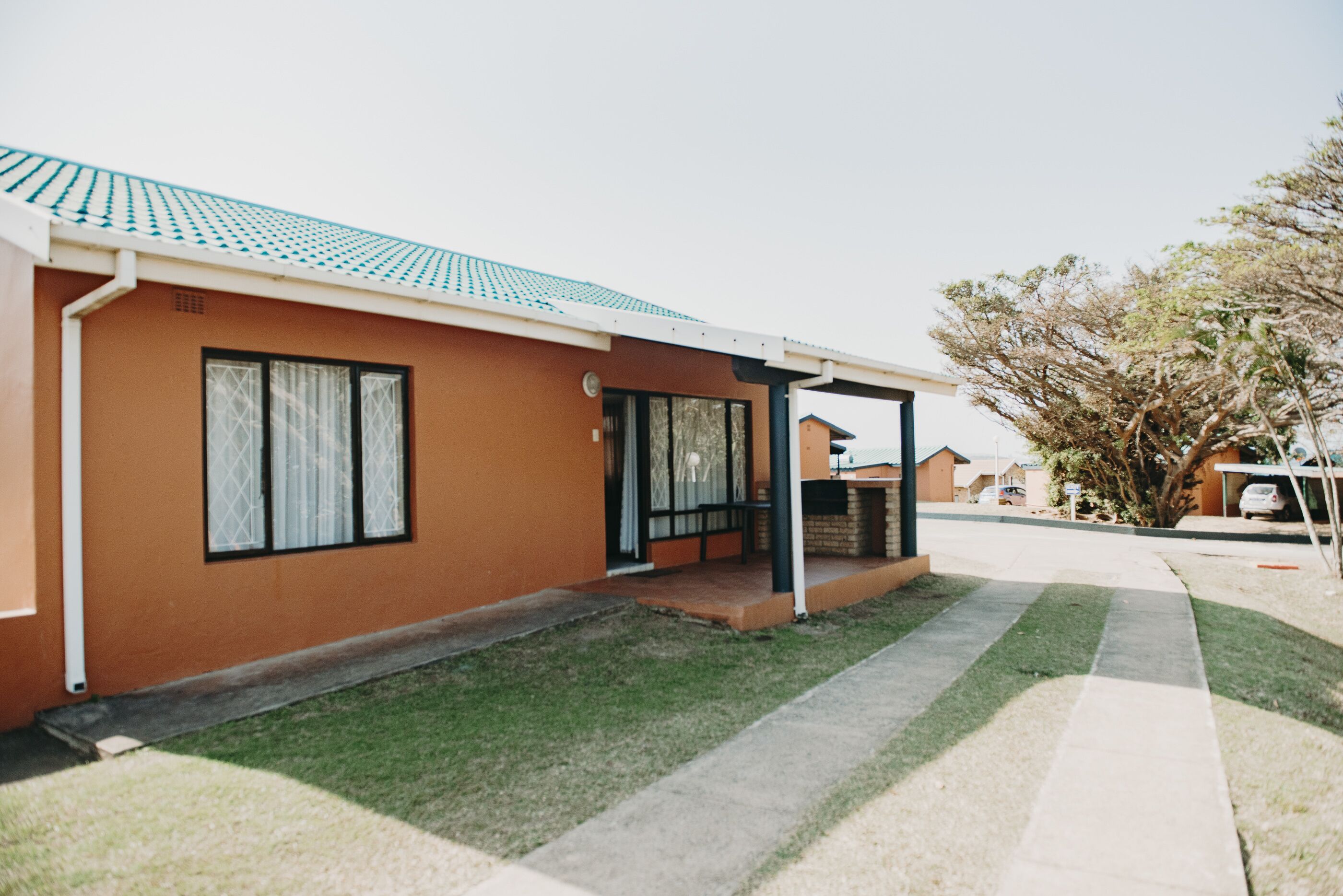 A single-story house with a brown exterior, a tiled roof, and a small porch.