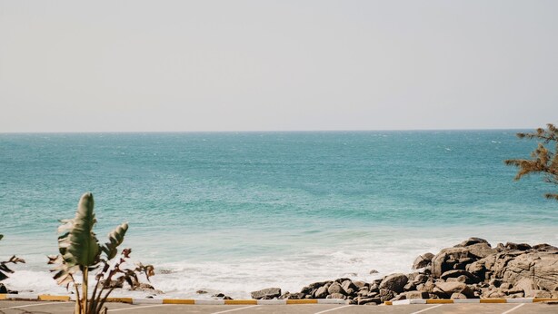 A coastal view with a rocky shoreline and a parking area in the foreground. - Port Edward Holiday Resort (Port Edward)