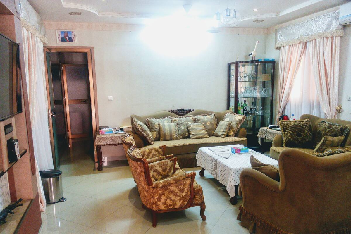 Una sala de estar con un sofá, sillones, una mesa de centro y un mueble con puertas de vidrio.