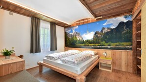 A wooden bedroom with a bed, a bench, a small table, and a large window. - Residence Treyer (Terento)