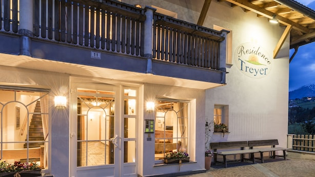 A hotel entrance with a sign reading "Residence Treyer" and a wooden balcony. - Residence Treyer (Terento)