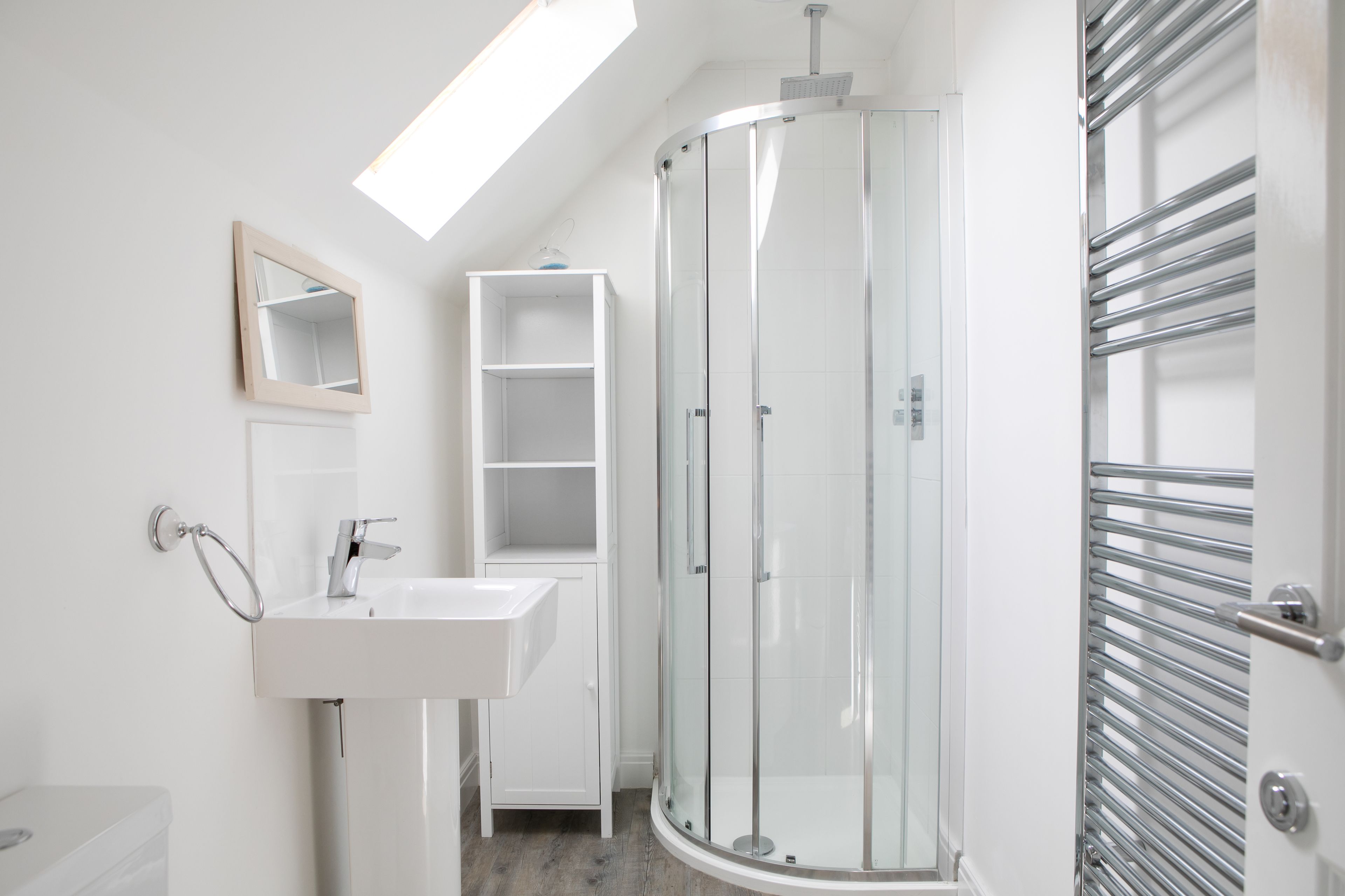 A modern bathroom with a glass shower enclosure, a white sink, and a built-in shelf.