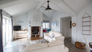 A spacious living area with a fireplace, white furniture, and a television.