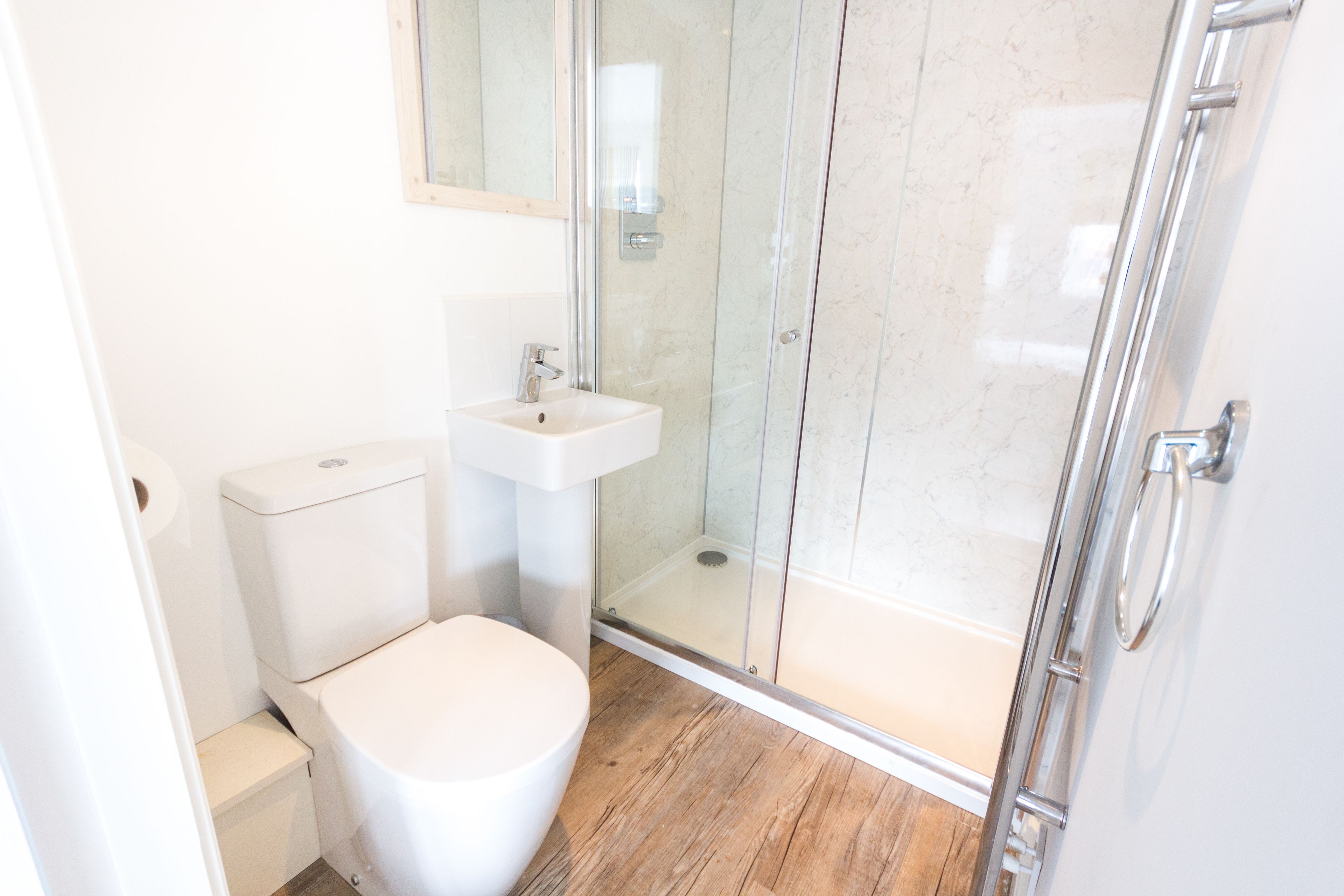 Ein modernes Badezimmer mit Toilette, Waschbecken und Duschkabine aus Glas.