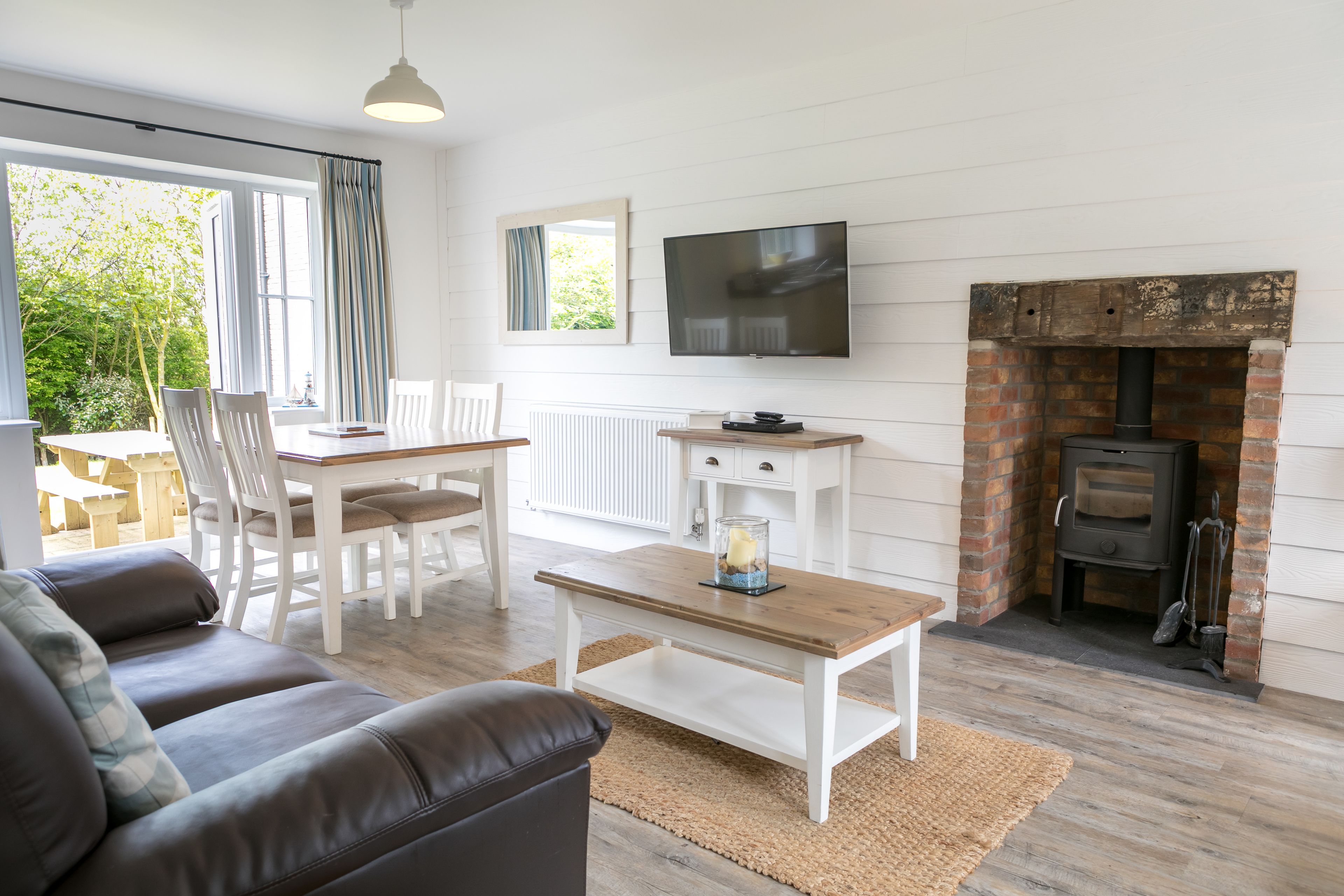 A living room with a sofa, a coffee table, a TV, a fireplace, and a dining area with chairs and a table.