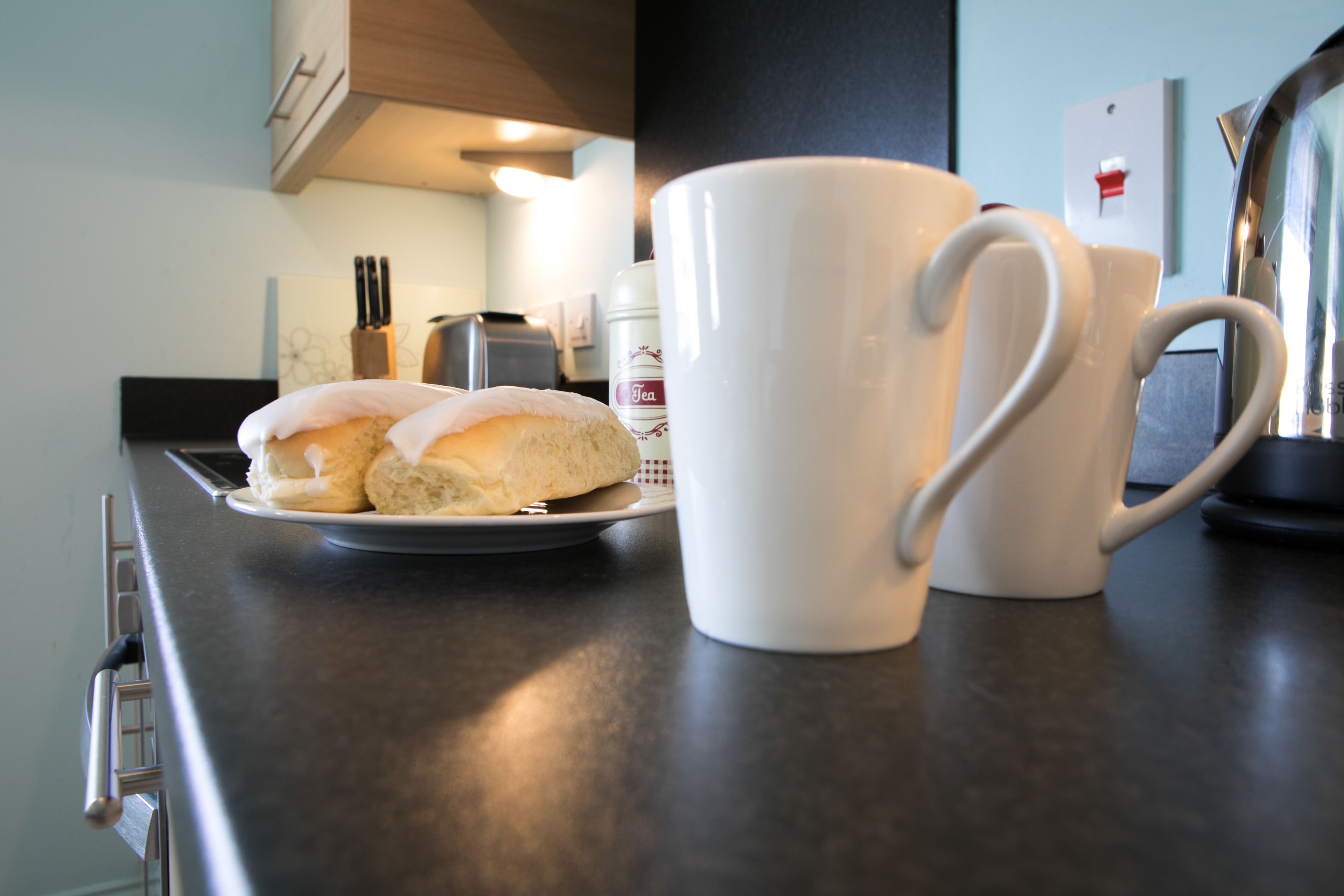 Un taulell de cuina amb un plat de galetes i dues tasses blanques.