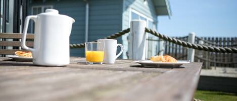 A wooden table with a white pitcher, a glass of orange juice, and a plate of food.