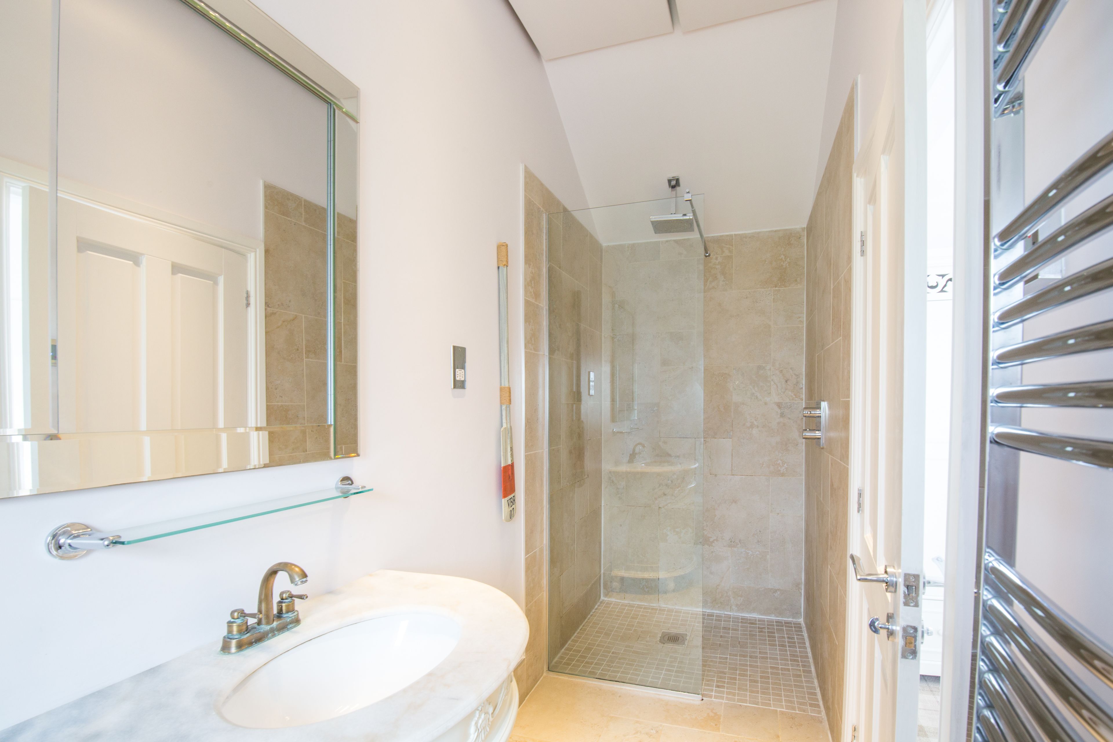 A modern bathroom with a glass shower enclosure, a marble sink, and a glass shelf.