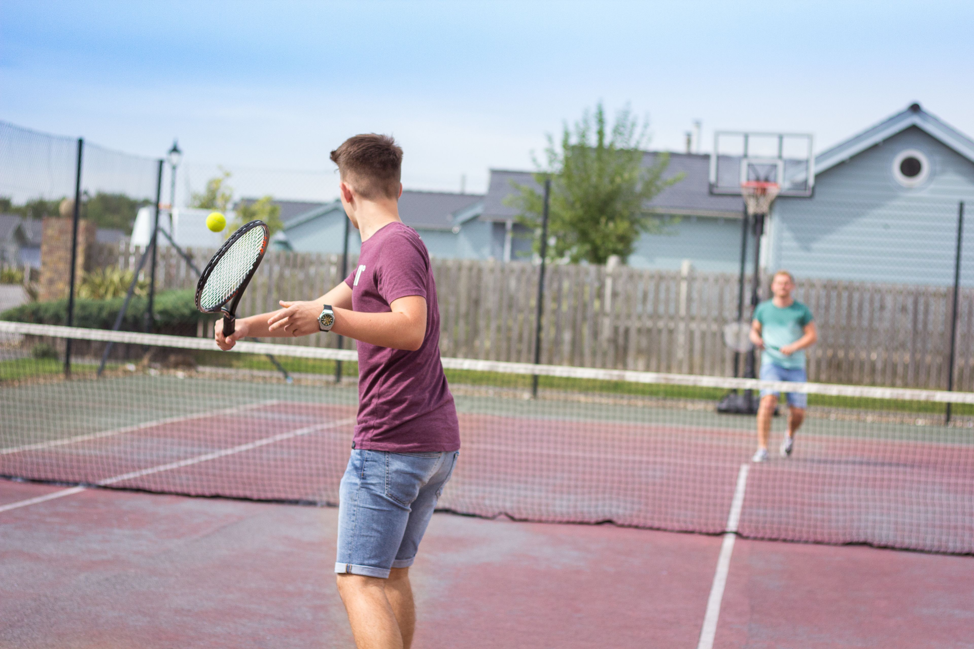Un court de tennis avec un filet au milieu, entouré d’une clôture.