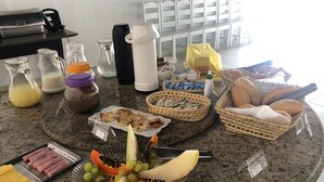 Una mesa de buffet con diversos alimentos, incluyendo frutas, pan y bebidas.