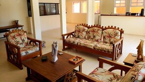 Una sala de estar con sofá, sillones, una mesa de centro y televisor.