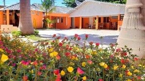 Un hotel con paredes exteriores anaranjadas, techo de tejas y un patio lleno de flores coloridas.