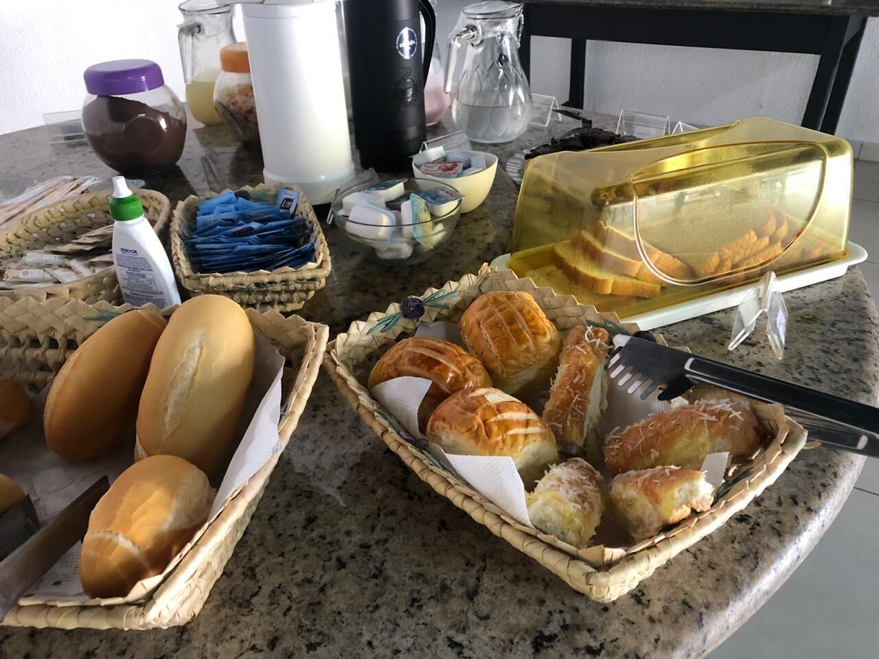 A kitchen counter with various food items, including bread, pastries, and condiments.