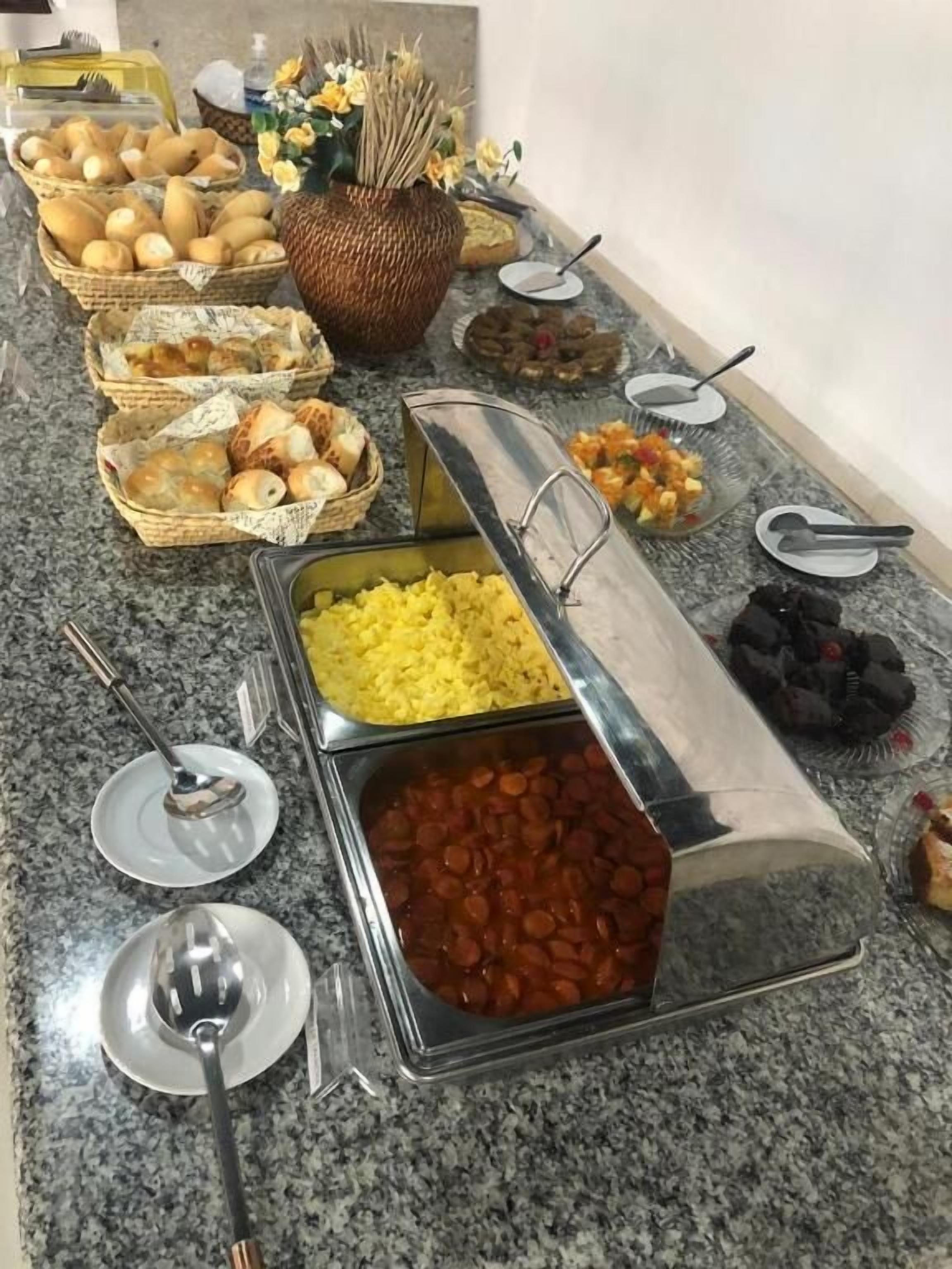 A buffet with various food items including bread, fruits, and a container of beans.