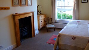 A bedroom with a bed, a dresser, a chair, a fireplace, and a window with curtains. - Grade II listed terraced house in Bath, Somerset (Bath)