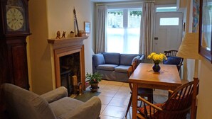A living room with a fireplace, a sofa, a dining table with chairs, and a clock on the wall. - Grade II listed terraced house in Bath, Somerset (Bath)