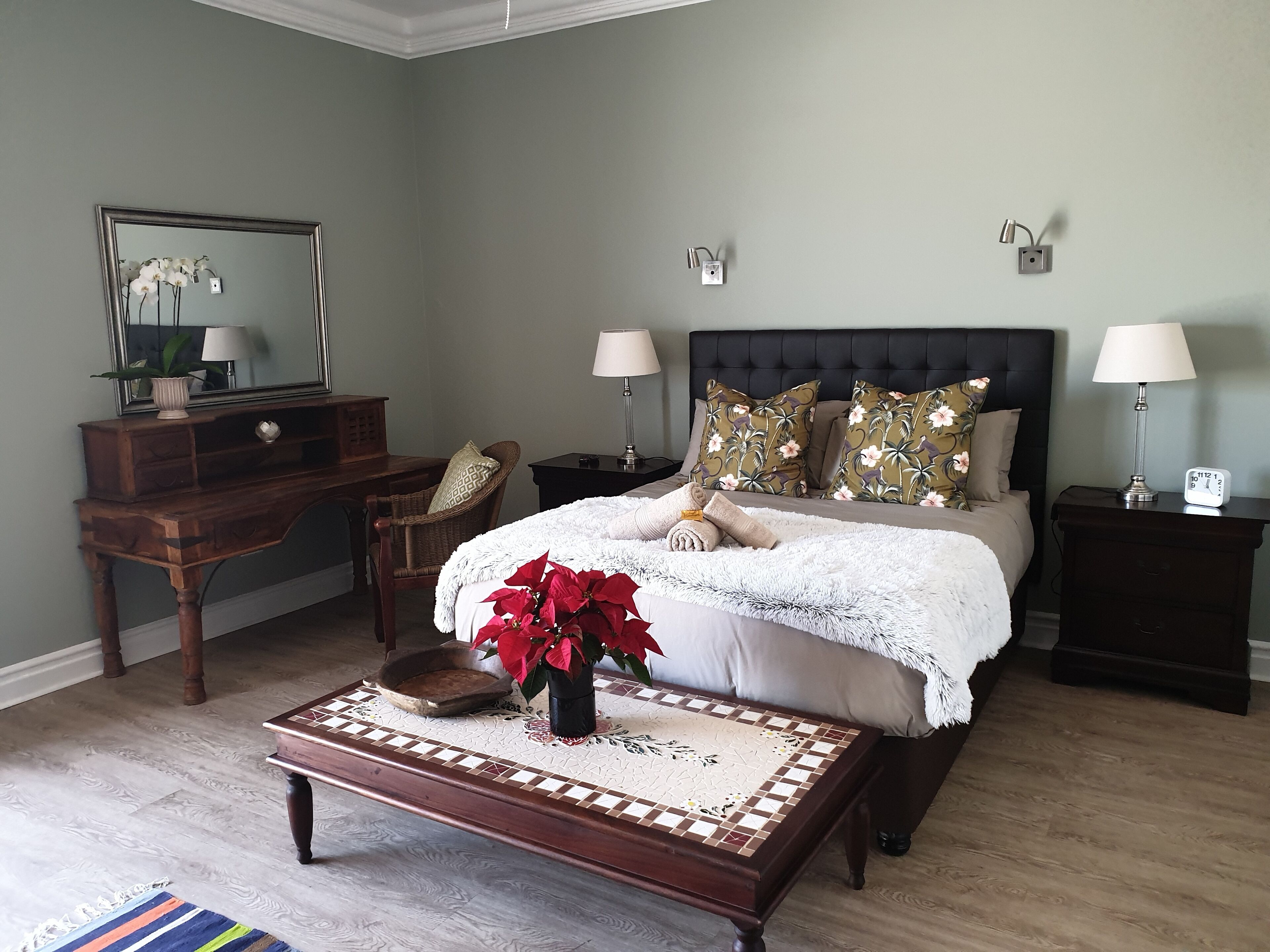 Quarto com cama, mesas de cabeceira, cómoda, espelho e mesinha de centro.