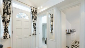 Un pasillo con puertas blancas, cortinas a cuadros en blanco y negro y un suelo de damero.