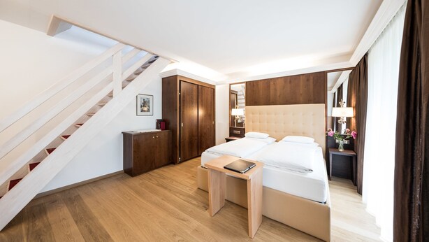 Un dormitorio moderno con una escalera de madera, una cama, una mesita de noche y un buró.