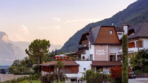 Un hotel llamado Haus am Hang con una terraza, rodeado de montañas y vegetación.