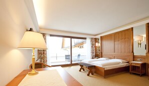 A hotel room with a bed, bedside table, lamp, and a large window offering a view of the outside. - Haus am Hang (Caldaro Sulla Strada del Vino)