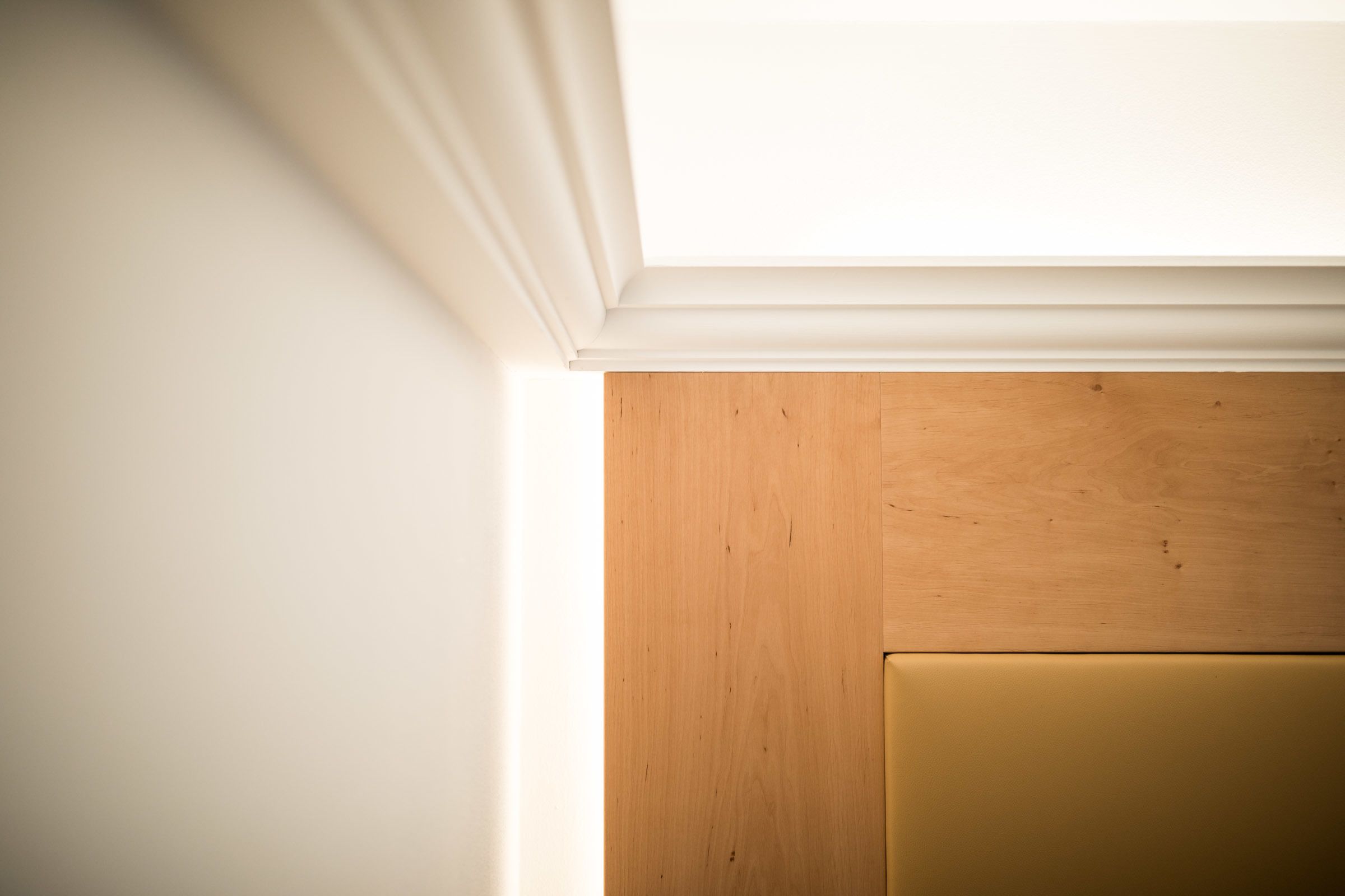 A corner of a room with a white wall and a wooden door frame.