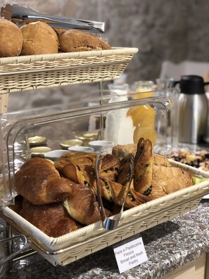 A buffet with bread and pastry options, including a sign indicating 'Pane e Pasticceria Fresca Bread and Fresh Pastry'.